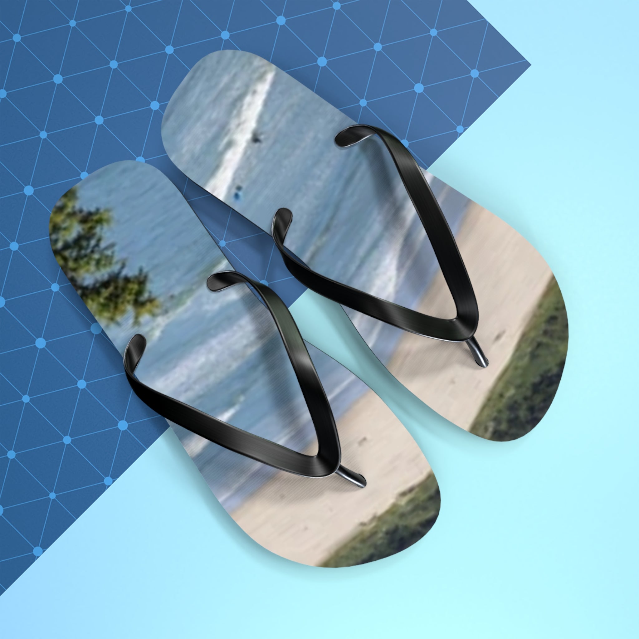 Flip-flops with a beach scene, resting on a blue patterned background.