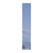 Tall, narrow image of a tall, rocky sea stack against a cloudy sky.