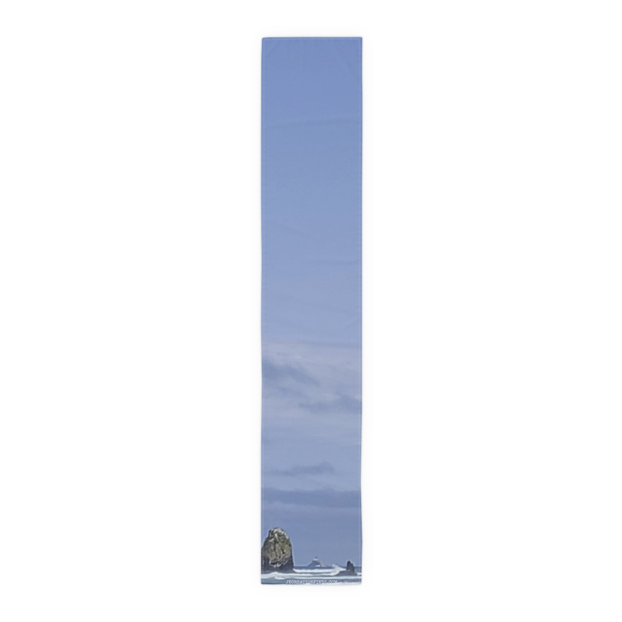 Tall, narrow image of a tall, rocky sea stack against a cloudy sky.