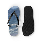 Two flip-flops on a white background, one showing the top with a beach scene, the other showing the sole.