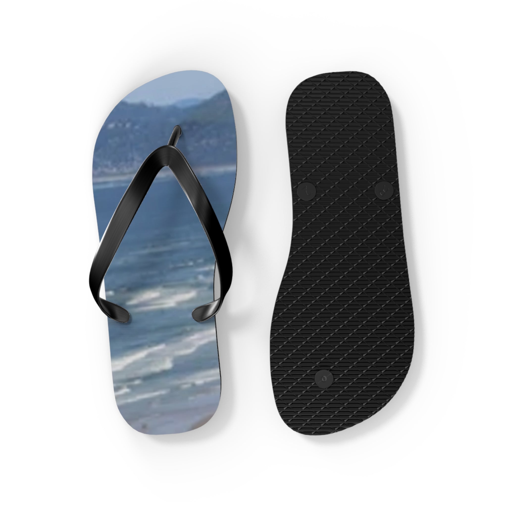 Two flip-flops on a white background, one showing the top with a beach scene, the other showing the sole.