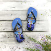 Blue flip-flops with "Laguna Beach" text and purple flowers on a wooden surface.