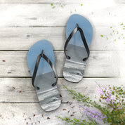 Blue flip-flops with ocean waves displayed on the straps, resting on a wooden surface.