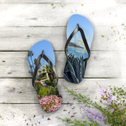 Flip-flops with beach and garden scenes on wooden deck with flowers.