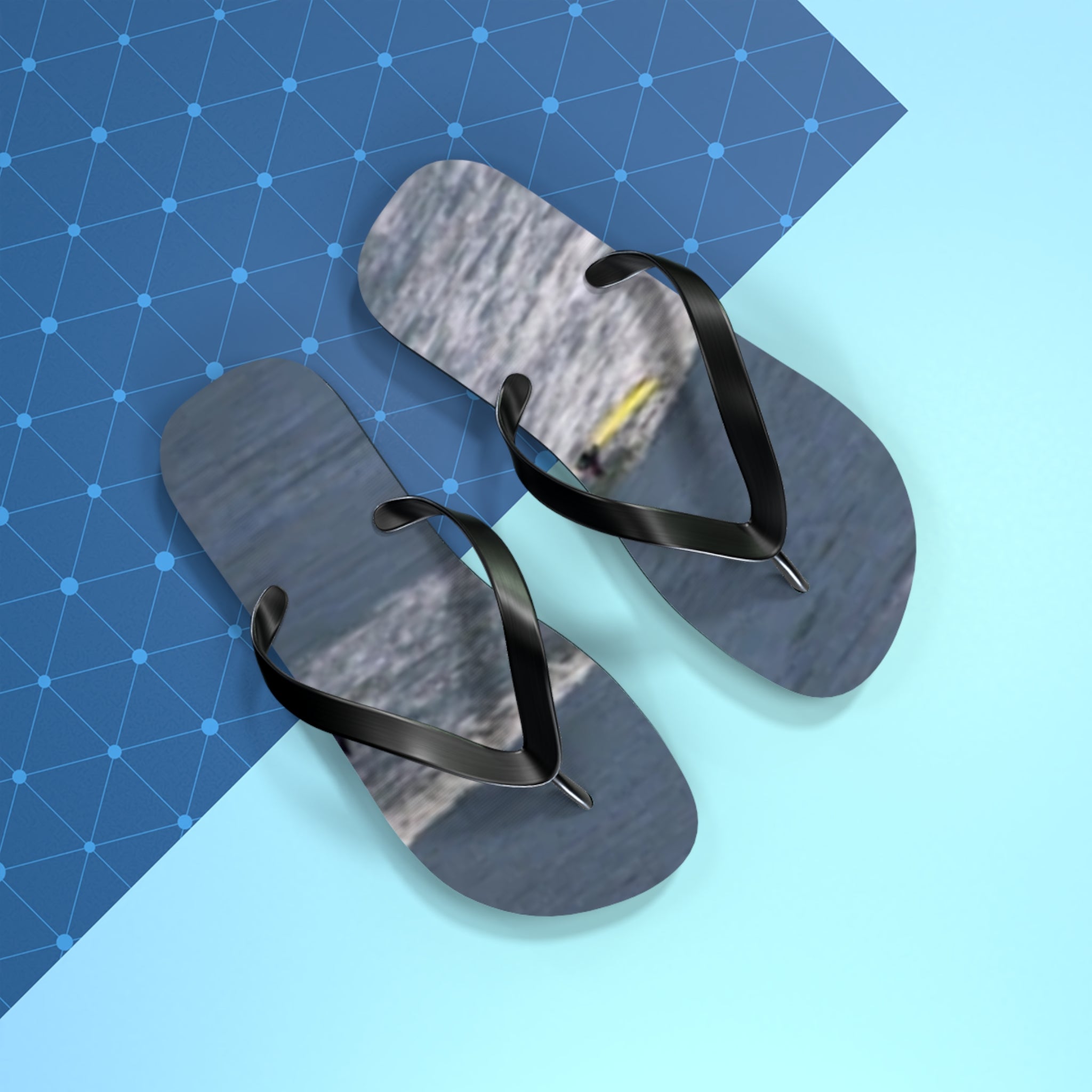 Black flip-flops with a textured gray footbed on a blue and white background.