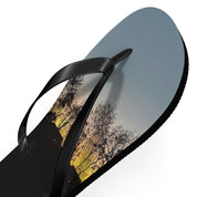 Black flip-flop with a sunset landscape printed on the sole.