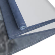 Rolled dark blue and gray fabric with white stitching against a white background.