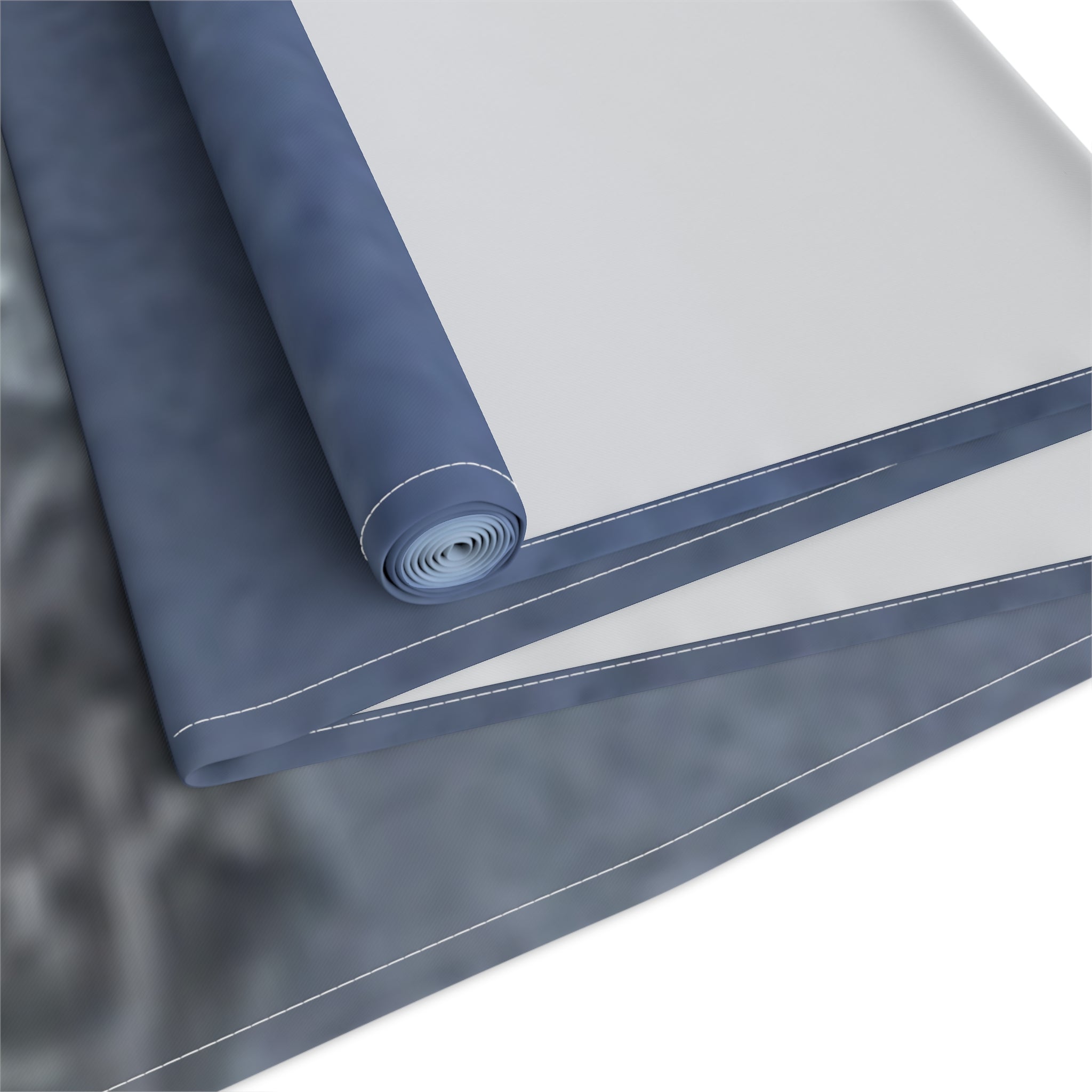 Rolled dark blue and gray fabric with white stitching against a white background.