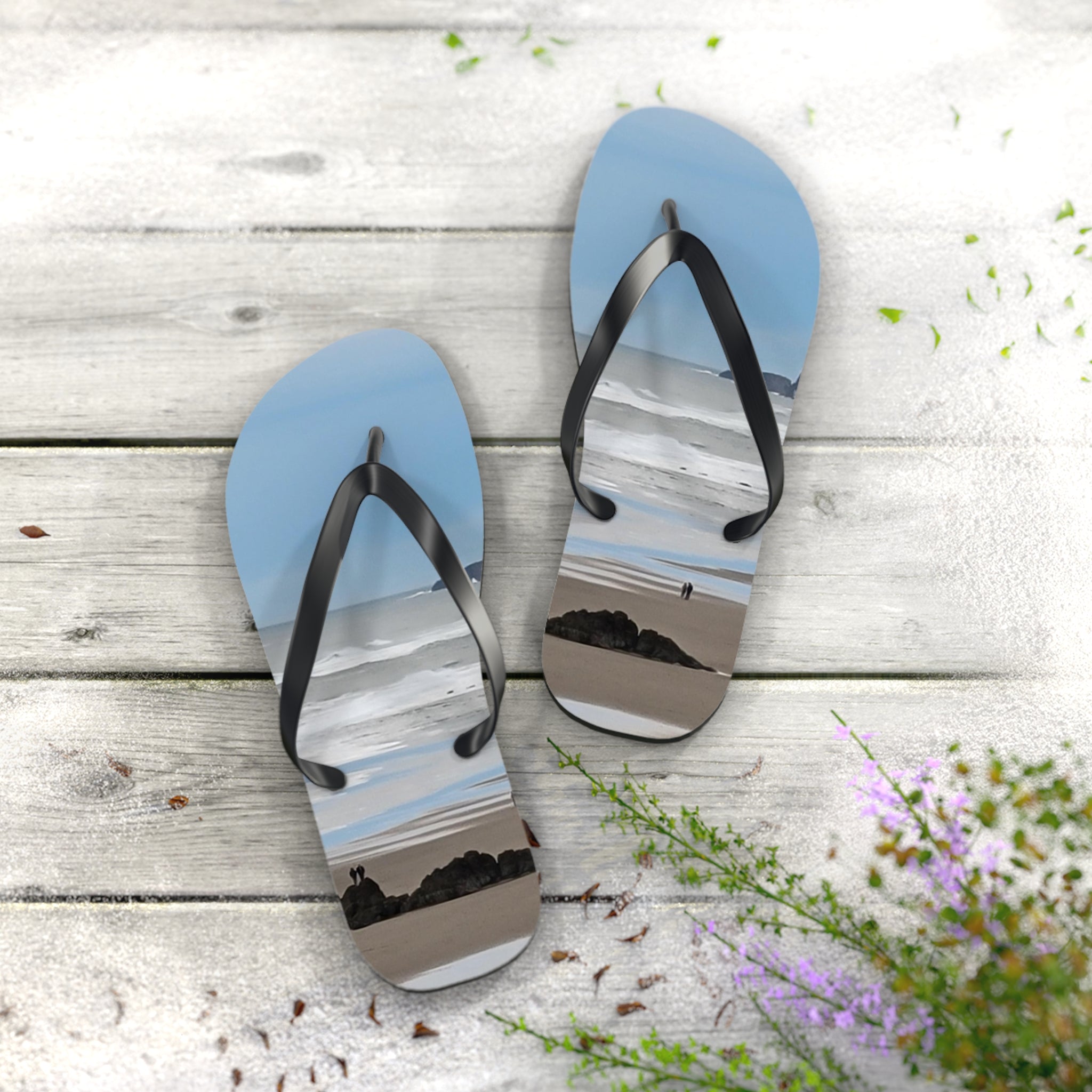Light blue flip-flops with beach scene graphic on weathered wood background.