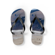 Flip-flops with a beach landscape and people walking on sand.