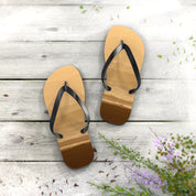 Brown flip-flops with beach scene printed on soles, on wooden planks.
