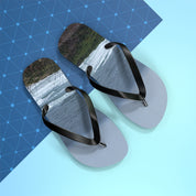 Flip-flops with a waterfall scene on the footbeds, against a blue grid background.
