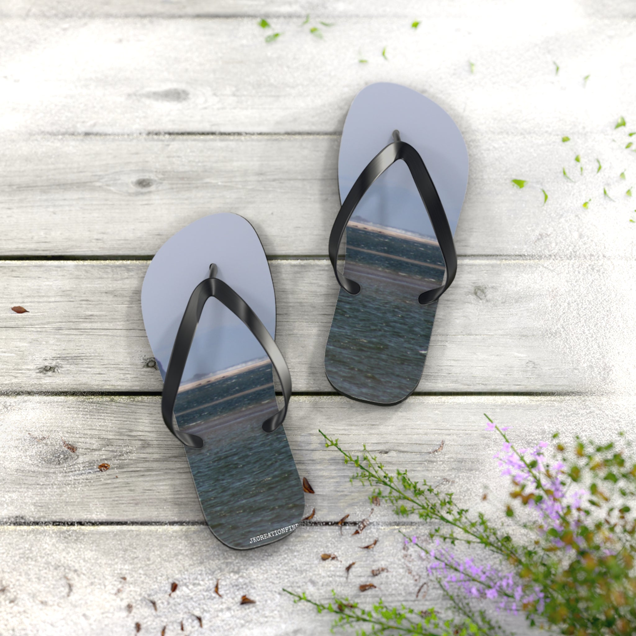 Light blue flip-flops with a water scene on the soles, on a wooden deck.