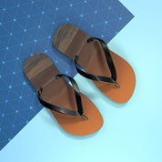 Brown flip-flops with black straps on a blue geometric background.