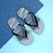 Flip-flops with a rainbow and ocean scene on a blue geometric background.