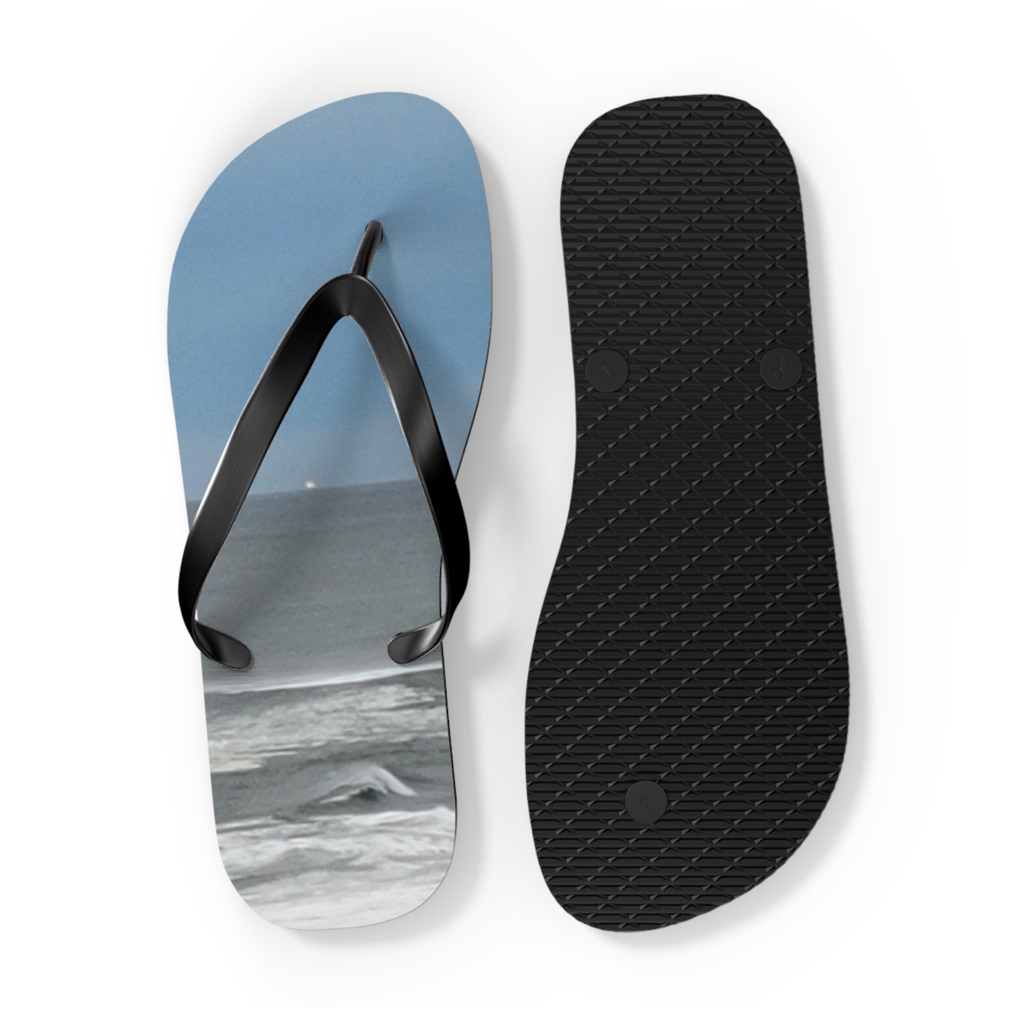 Flip-flops with a beach scene on one sole and a black textured sole.