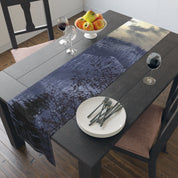 Dark forest and cloudy sky reflected in water on a table runner.