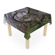 Green moss-covered tree branches draped over a square tablecloth.