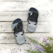 Pair of flip-flops with ocean waves pattern on wooden deck.