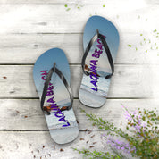 Flip-flops with "Laguna Beach" text and ocean view on a wooden surface.