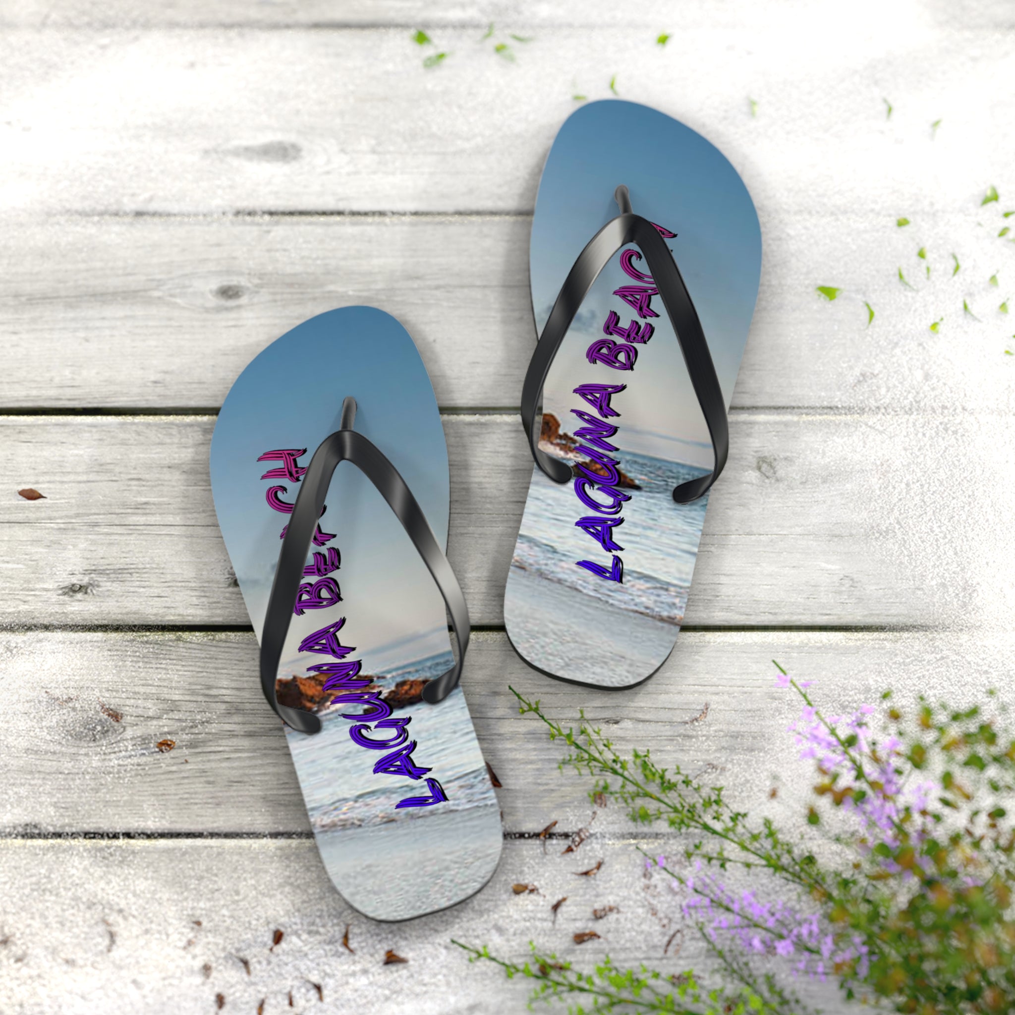 Flip-flops with "Laguna Beach" text and ocean view on a wooden surface.