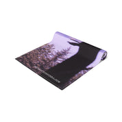 Rolled yoga mat with a silhouette of a person reaching up against a blurred background.