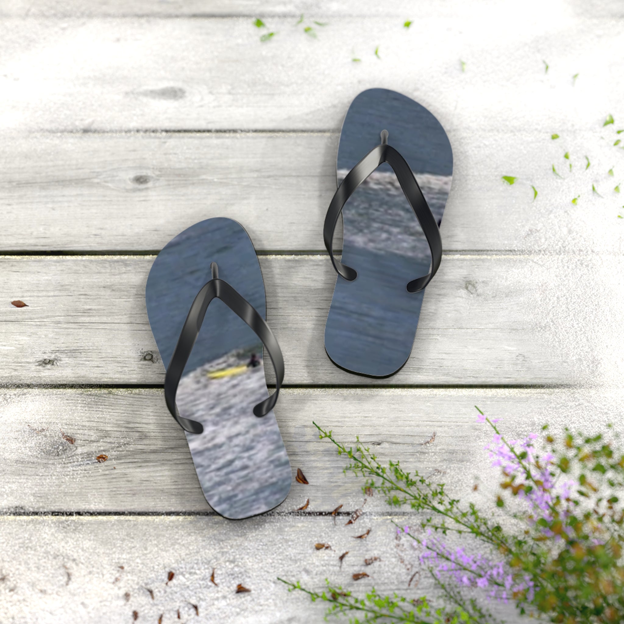 Black flip-flops with waves on the straps, on a white wooden surface.