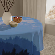 Blue tablecloth with cloud and forest pattern on round table.