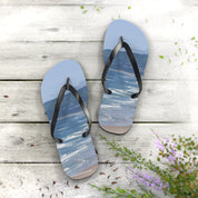 Flip-flops with a beach and ocean scene on a wooden surface.