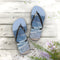 Flip-flops with a beach and ocean scene on a wooden surface.