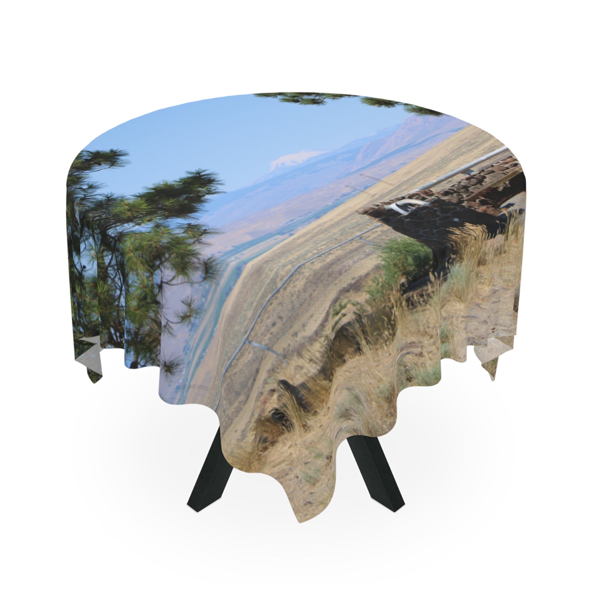 Round tablecloth with a landscape print of dry grass, mountains, and trees.