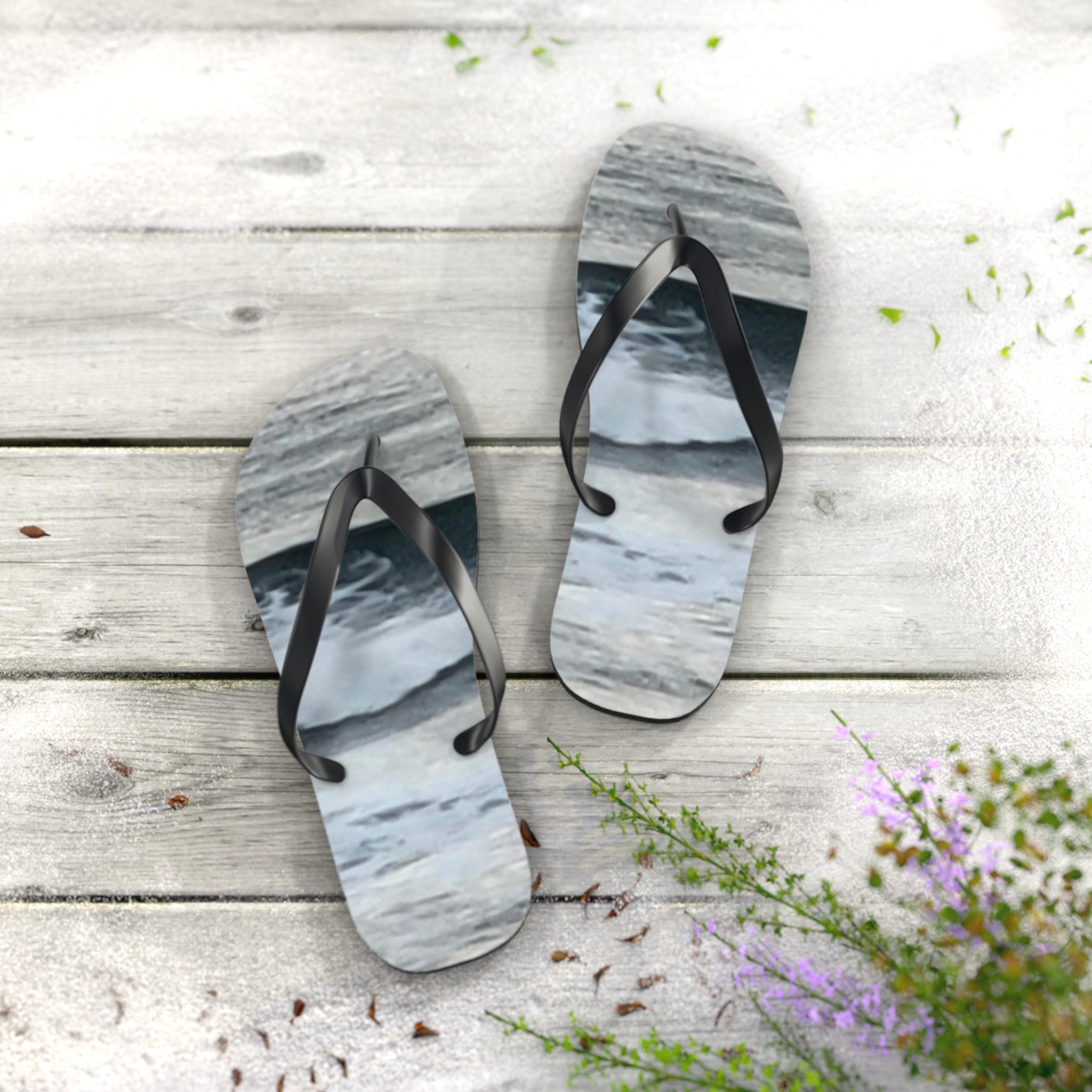 Beach scene flip-flops on a light wooden deck with scattered petals.