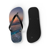 Black flip-flops with a sunset ocean wave design on one sole.