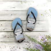 Blue flip-flops with a beach scene design on a weathered wood surface.
