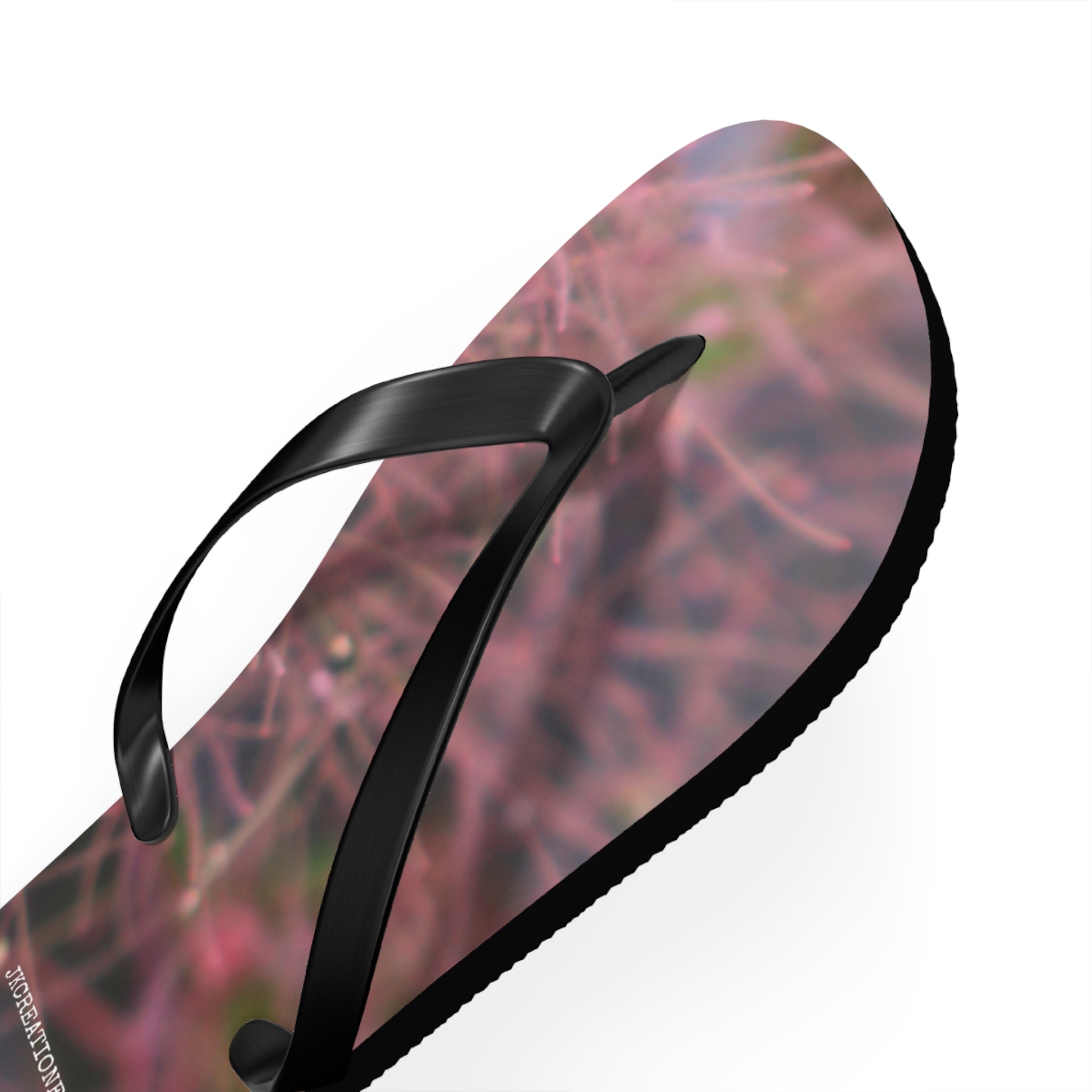 Black flip-flop sandal with a blurred pink and green floral pattern on the sole.