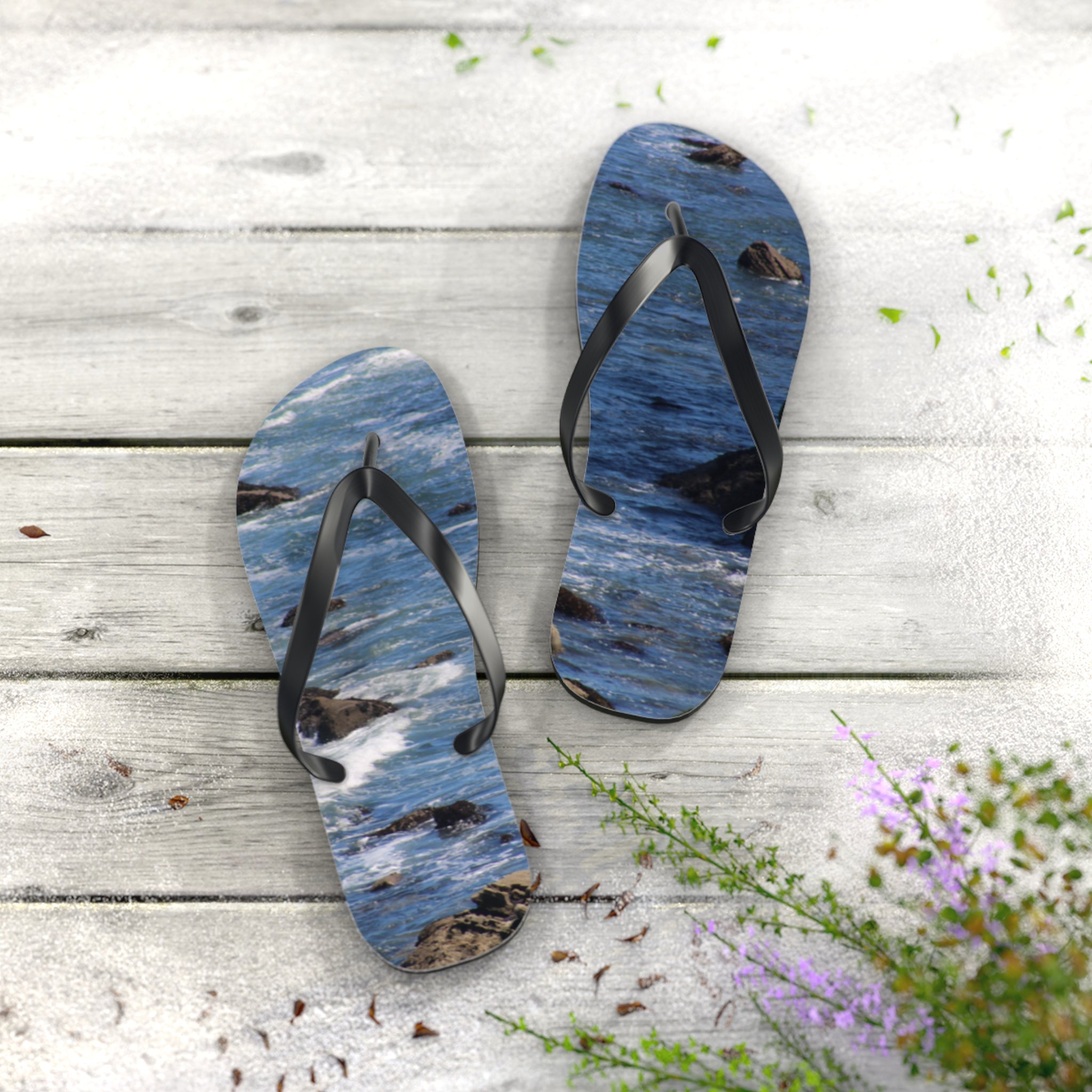 Ocean wave pattern flip-flops on a wooden surface with scattered leaves.