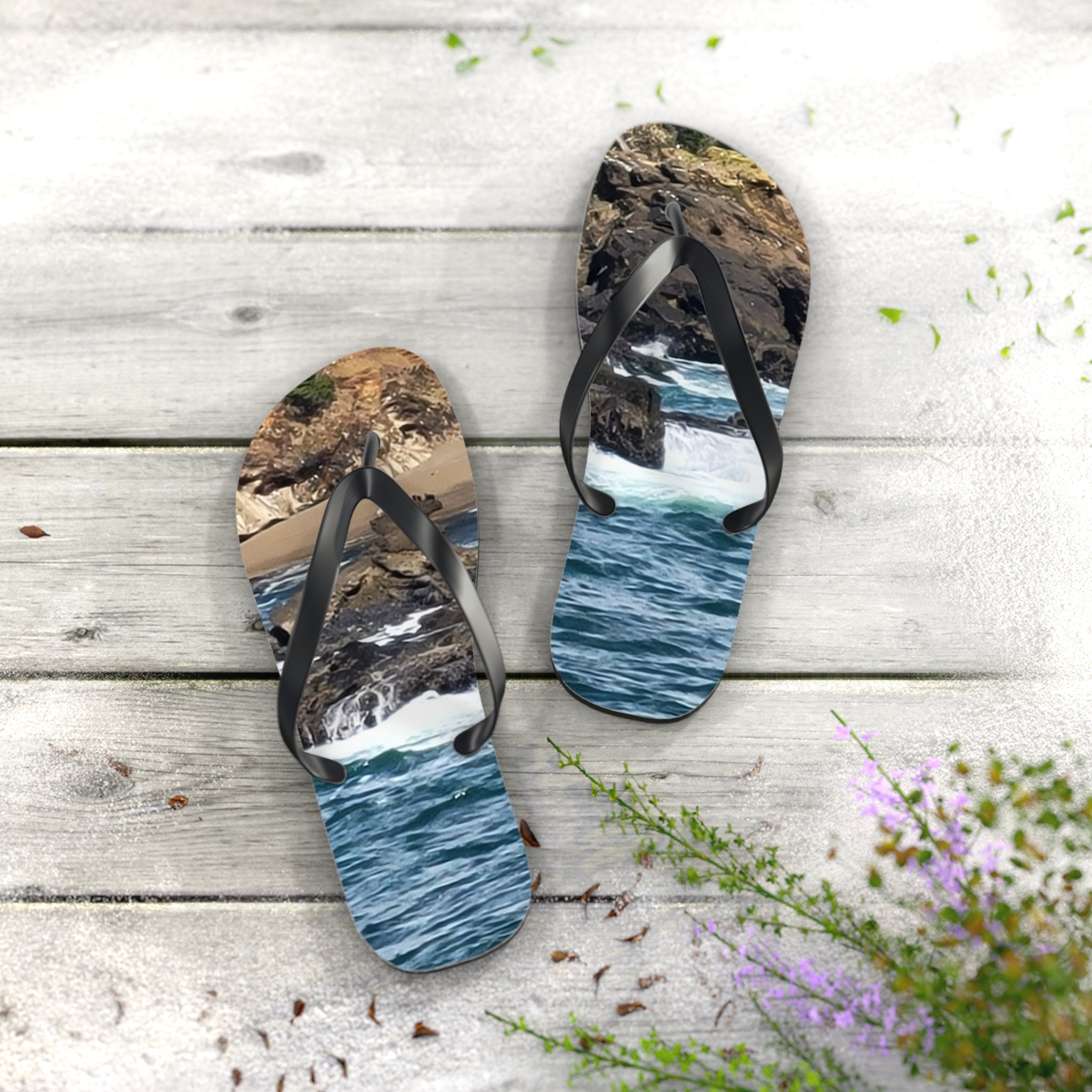 Flip-flops with ocean wave and rocky shore scene on soles, on wood.