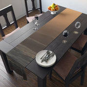 Dark wooden dining table with runner, plates, and wine glasses.