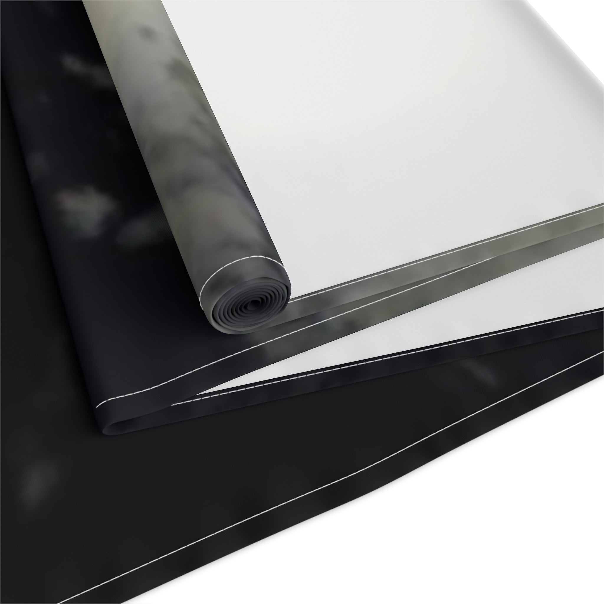 Black and white fabric unrolled, showing a dark patterned section and a white section.