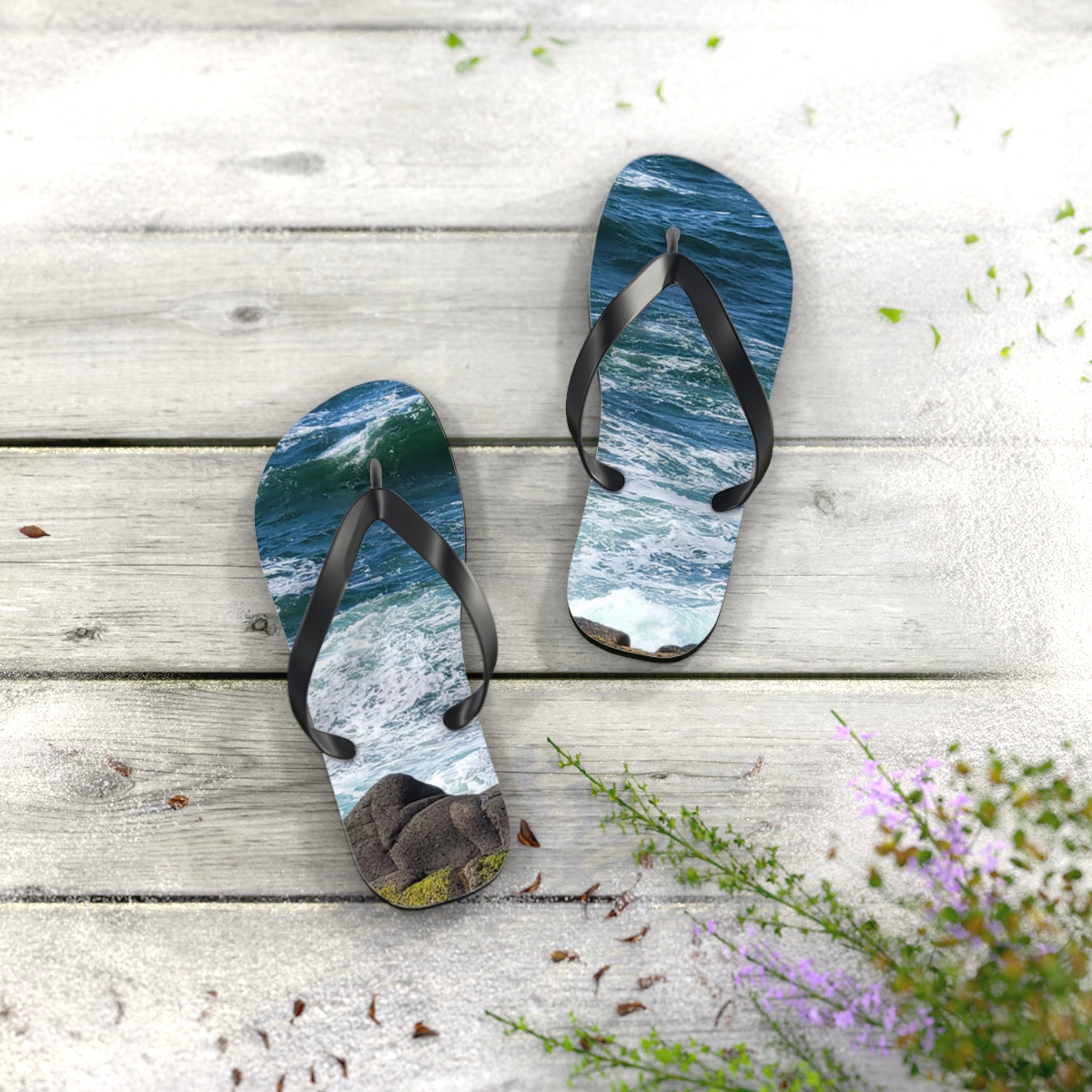 Flip-flops with ocean waves on white wooden planks and scattered sand.