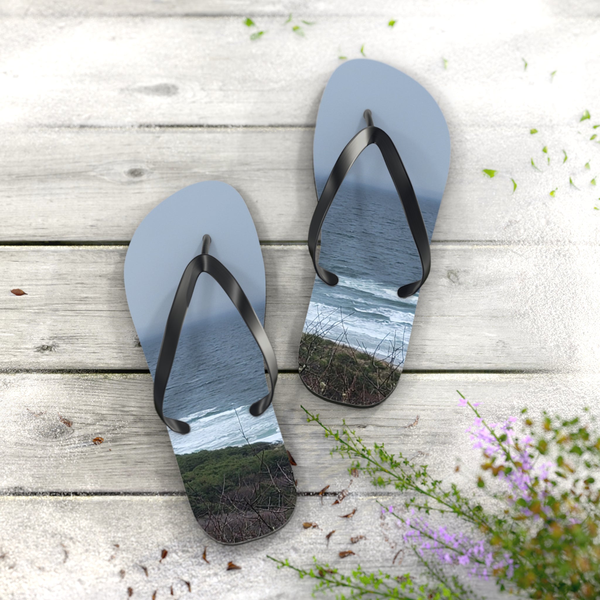 Light blue flip-flops with ocean and forest scene on wooden planks.