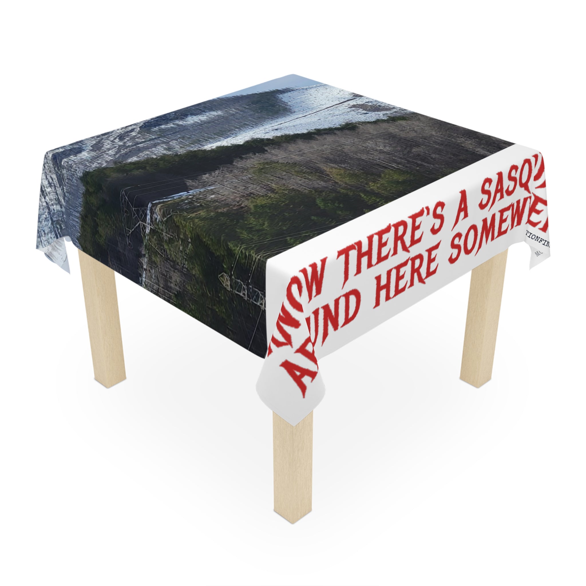 Tablecloth with "ANYWAY THERE'S A SASQUATCH AROUND HERE SOMEWHERE" text over forest and water.