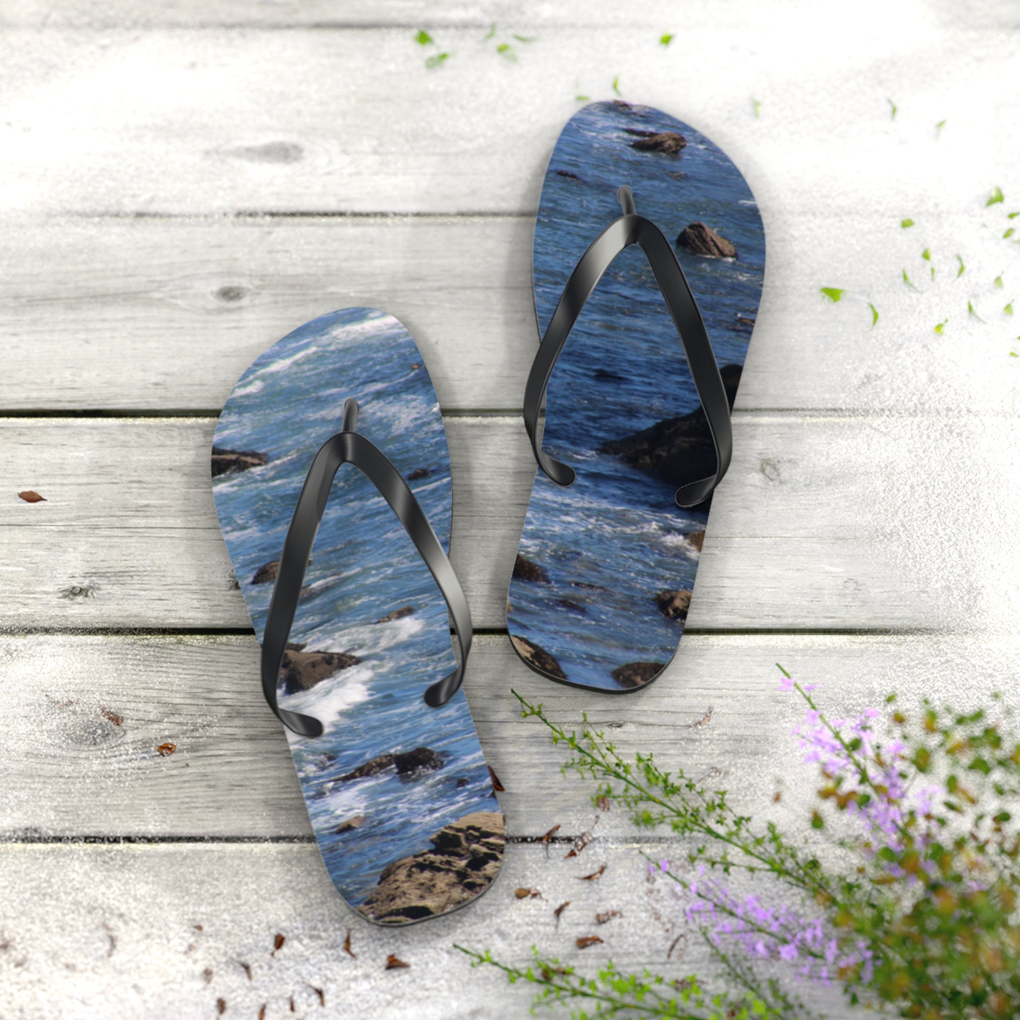 Flip-flops with a rocky ocean wave design on a wooden surface.
