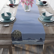 Table runner with a blurry seascape design of a lighthouse and rocks.