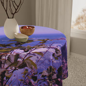 Round tablecloth with a landscape scene and leaves, featuring a white vase and bowl.