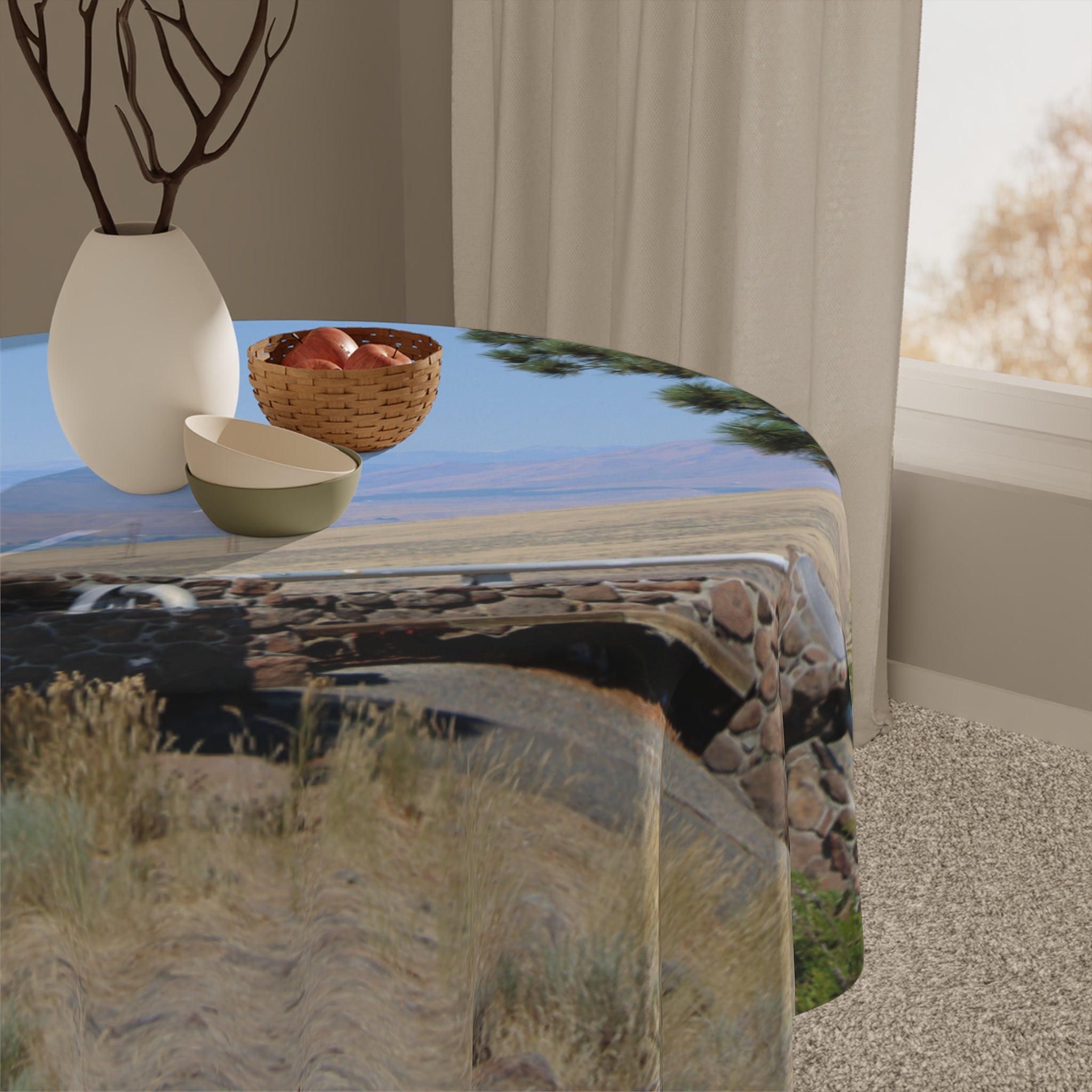 Round tablecloth with outdoor scenic print and woven basket.