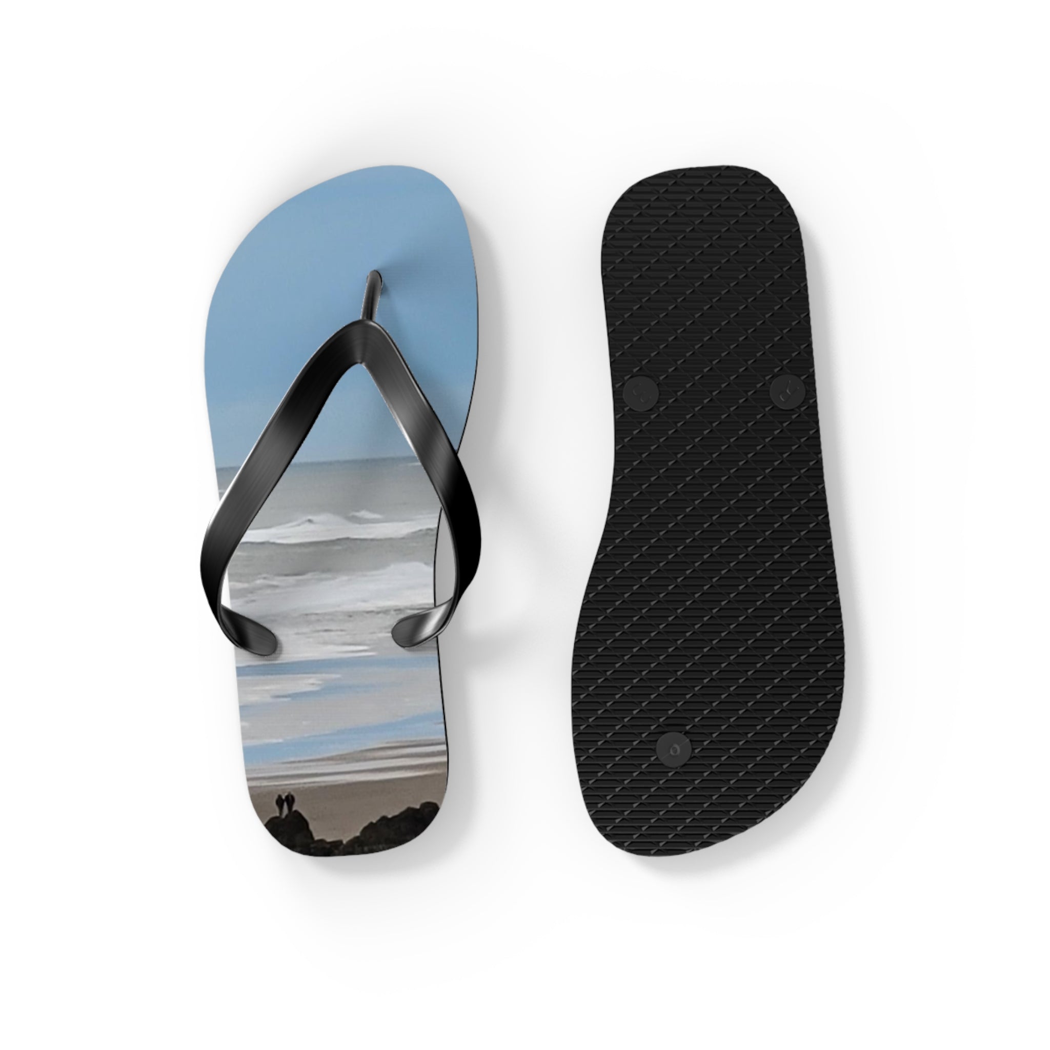 Black flip-flops with beach scene on left strap, white sole.