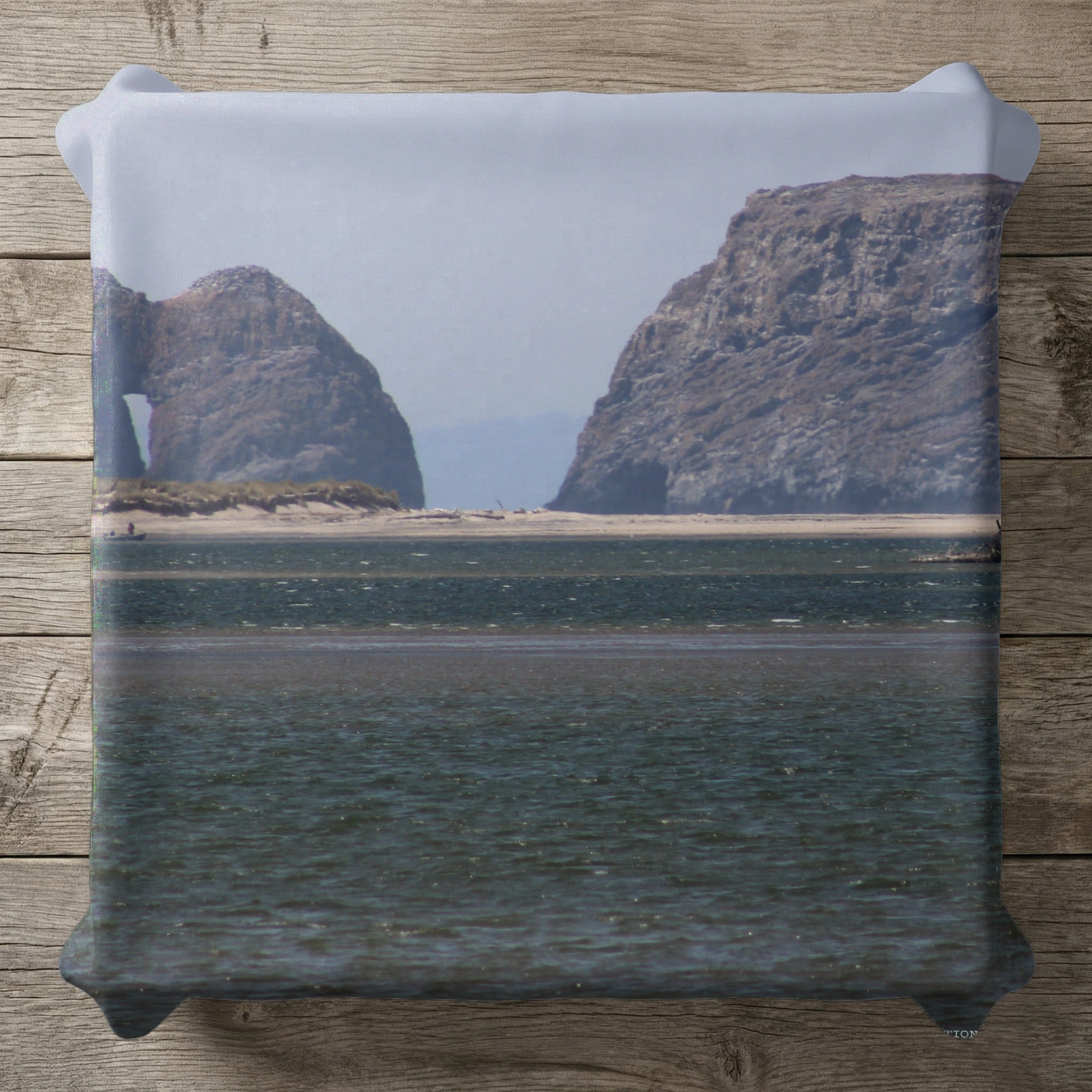 Rocky coastal arch and formations with calm water in the foreground.