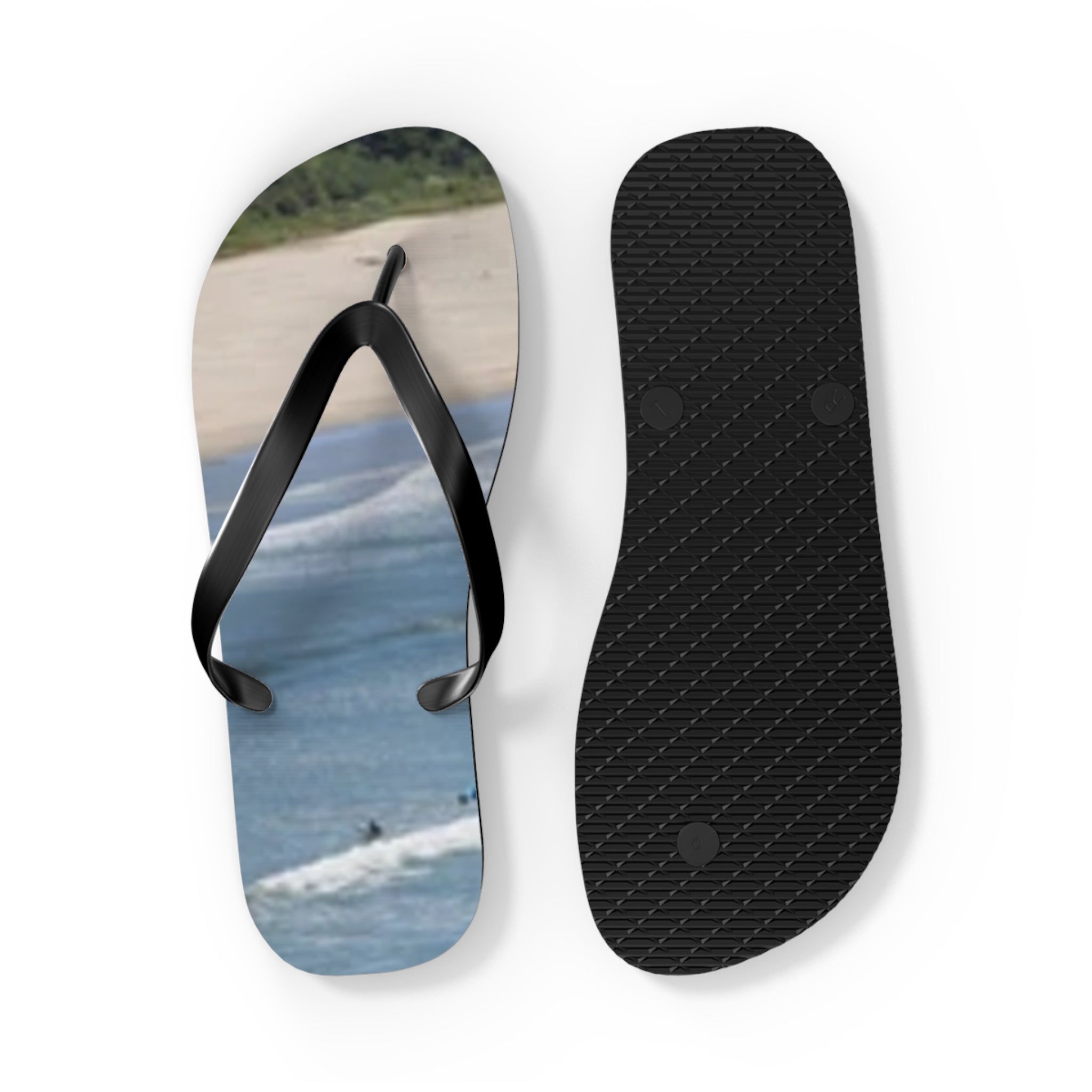 Black flip-flops with a beach and ocean scene printed on the right sole.