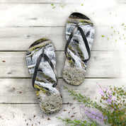 Flip-flops with a waterfall scene on a wooden deck with small plants.